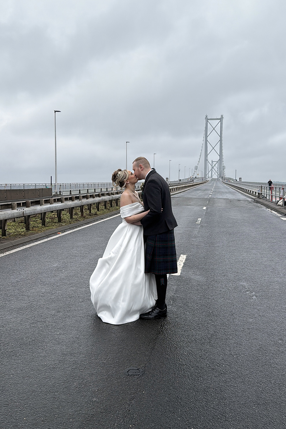 Bride and groom kiss on bridge